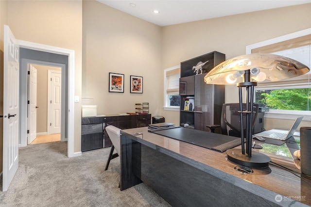 office space featuring light carpet, a high ceiling, baseboards, and recessed lighting