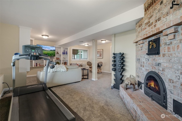 exercise area with carpet floors, a brick fireplace, and baseboards