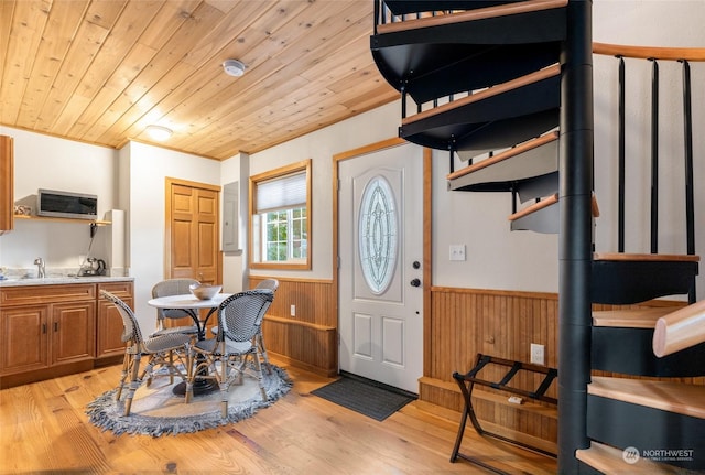 entryway featuring light wood-type flooring, wood walls, wood ceiling, and wainscoting