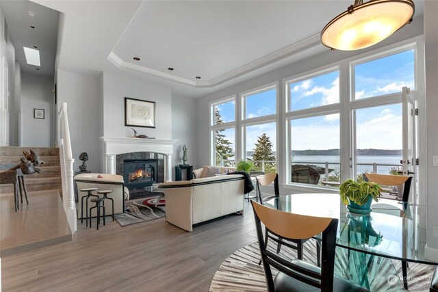 living room with a water view, hardwood / wood-style floors, a tiled fireplace, and a raised ceiling