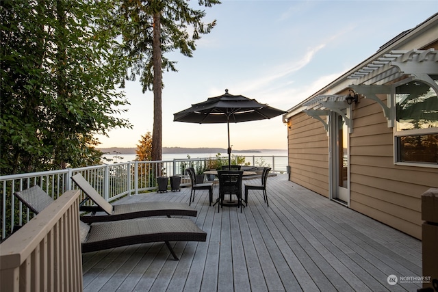 deck at dusk with a pergola and a water view