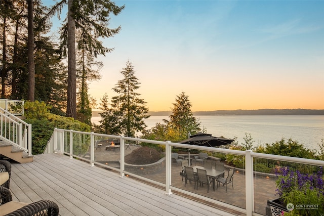 deck at dusk featuring a water view