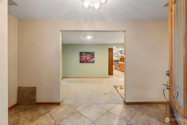 corridor featuring a textured ceiling, tile patterned flooring, and baseboards