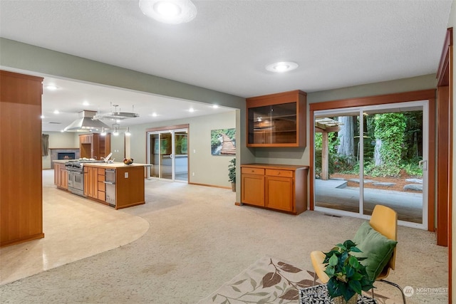 kitchen with recessed lighting, light carpet, open floor plan, ventilation hood, and high end stainless steel range oven