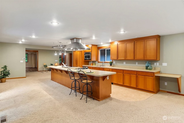 kitchen featuring stainless steel oven, a breakfast bar area, a kitchen island, and light carpet