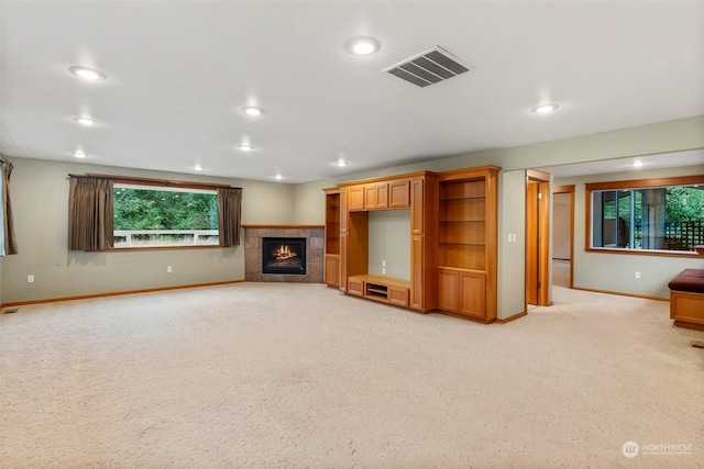 unfurnished living room featuring light carpet, visible vents, baseboards, a tile fireplace, and recessed lighting