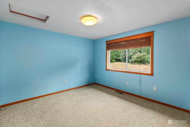 empty room with carpet, attic access, visible vents, and baseboards