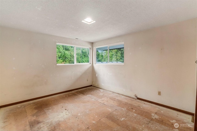 unfurnished room with a textured ceiling and baseboards