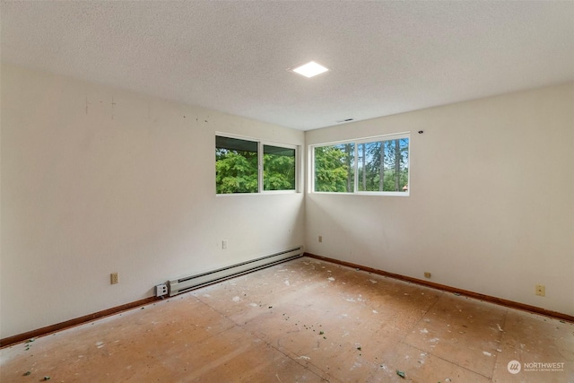 spare room featuring baseboards, baseboard heating, and a textured ceiling