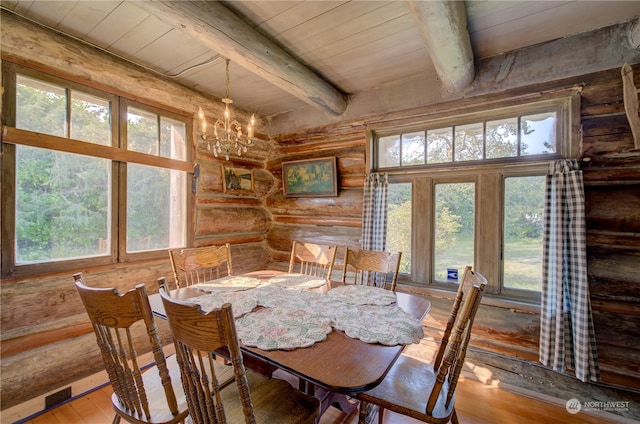 dining space with beamed ceiling, hardwood / wood-style flooring, log walls, and a healthy amount of sunlight