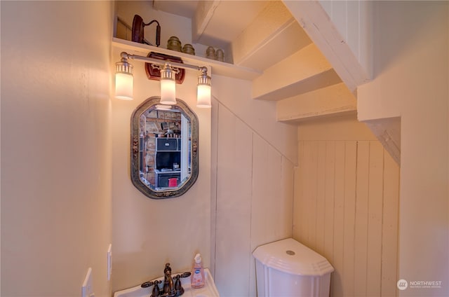 bathroom featuring wooden walls and sink