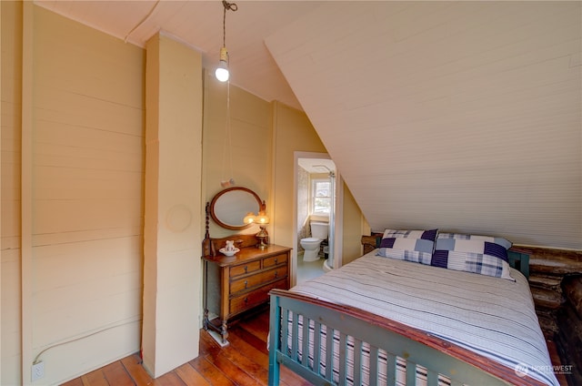 bedroom with vaulted ceiling, hardwood / wood-style floors, and connected bathroom