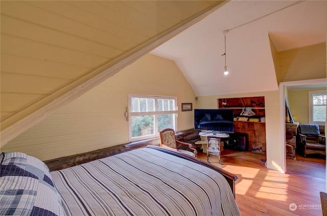 bedroom with vaulted ceiling, hardwood / wood-style floors, and multiple windows