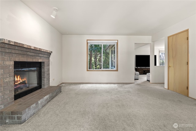 unfurnished living room with a fireplace, light carpet, and a healthy amount of sunlight