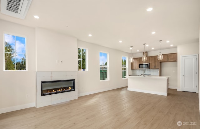 unfurnished living room featuring a tiled fireplace, light hardwood / wood-style flooring, and sink