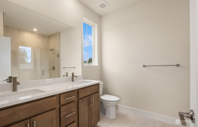 bathroom with tile patterned floors, a shower with door, vanity, and toilet