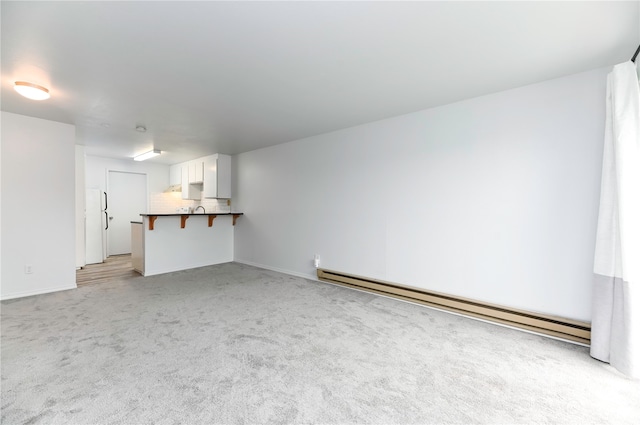 unfurnished living room featuring baseboard heating and light carpet