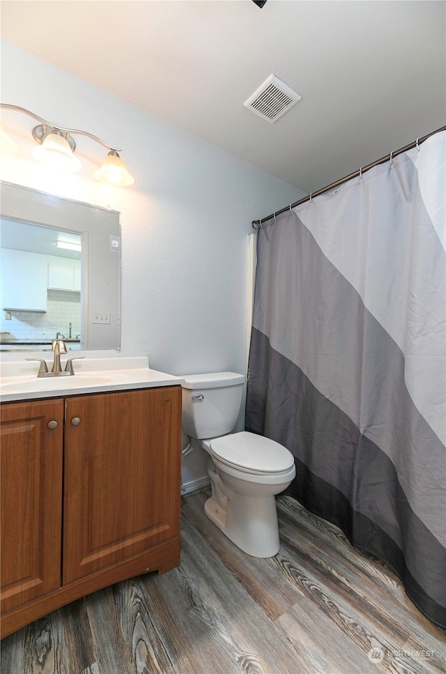 bathroom with hardwood / wood-style floors, a shower with curtain, toilet, and vanity