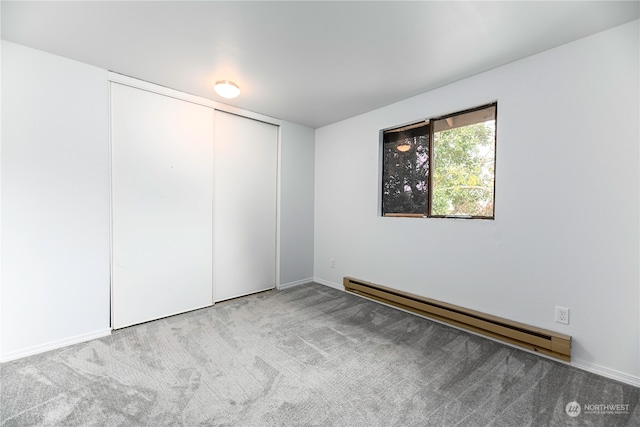 interior space with a baseboard heating unit, a closet, and carpet flooring