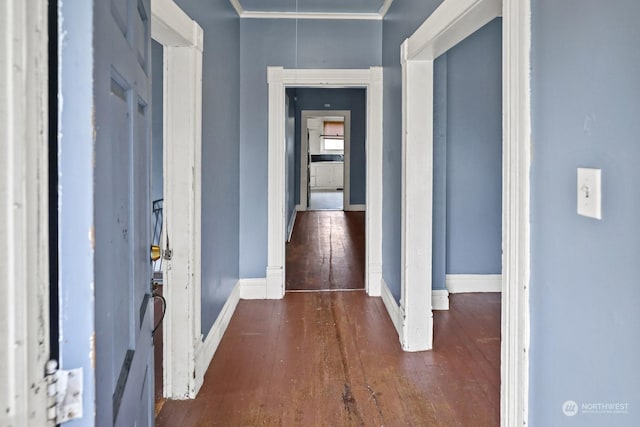 hallway featuring attic access, crown molding, baseboards, and wood-type flooring