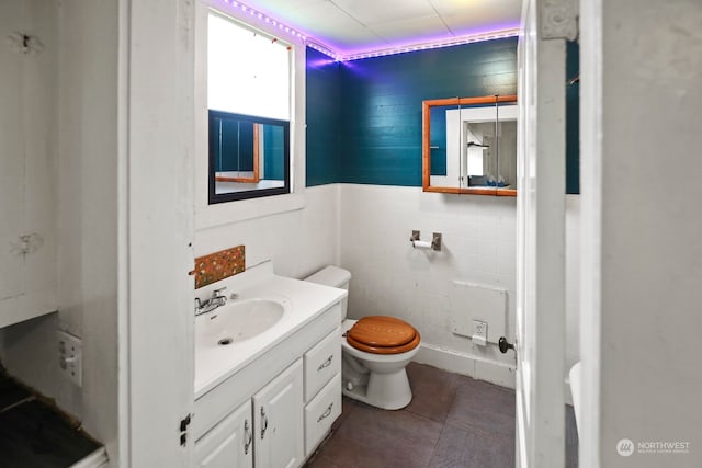 bathroom with vanity, toilet, tile walls, and tile patterned floors