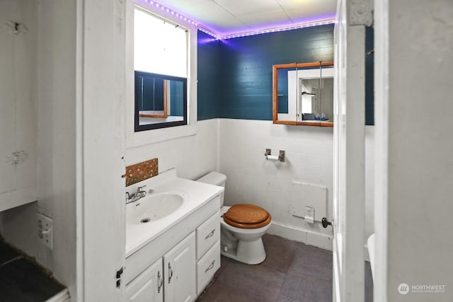 half bathroom with vanity, tile walls, toilet, and tile patterned flooring