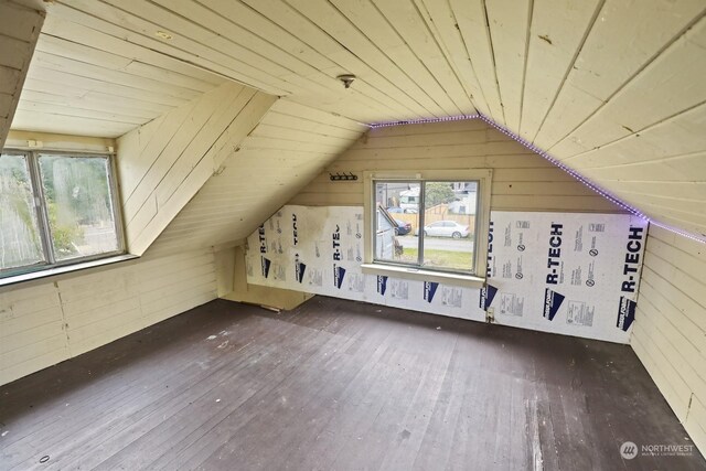 additional living space with lofted ceiling, wood ceiling, wood-type flooring, and wooden walls