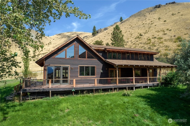 back of house with a deck with mountain view and a yard