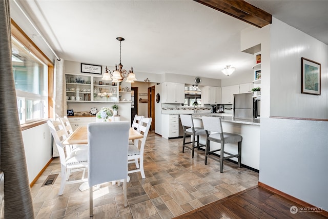 dining room featuring hardwood / wood-style flooring, beam ceiling, and a notable chandelier