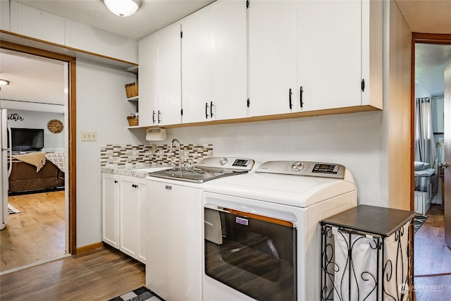 laundry area with dark hardwood / wood-style floors, sink, cabinets, and separate washer and dryer