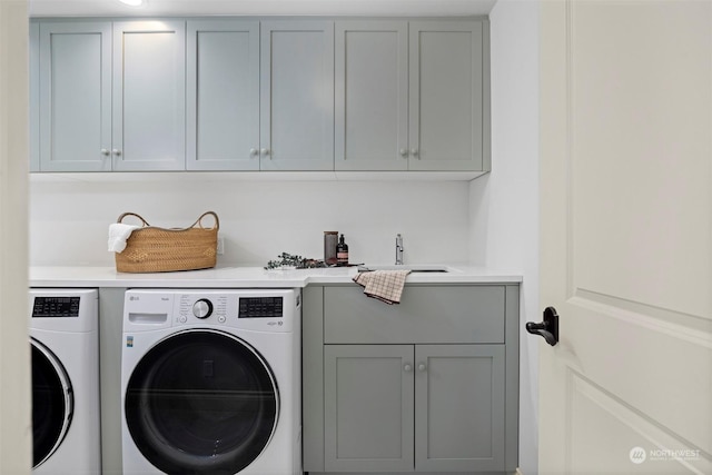 laundry room with cabinet space, separate washer and dryer, and a sink