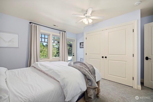 bedroom with a closet, visible vents, ceiling fan, and light carpet