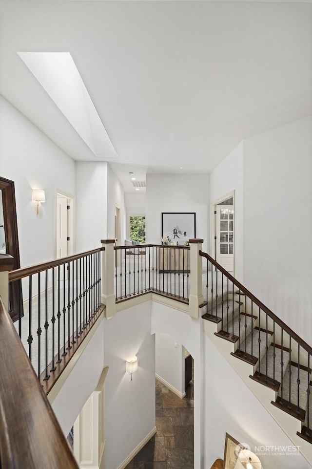 staircase with a towering ceiling, baseboards, and stone finish floor