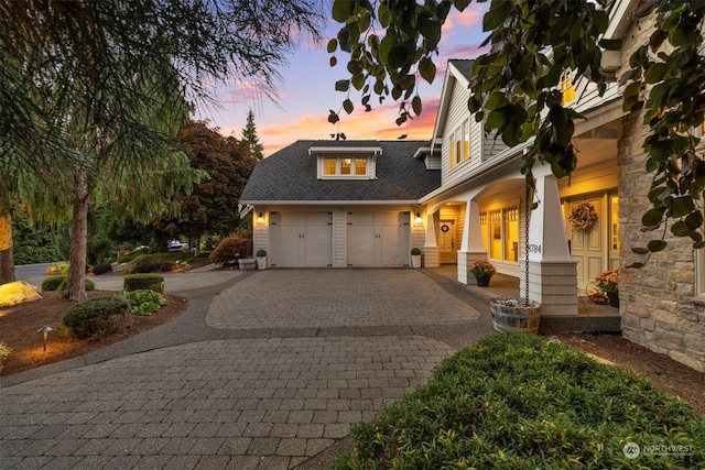 view of front facade with stone siding, decorative driveway, covered porch, and an attached garage