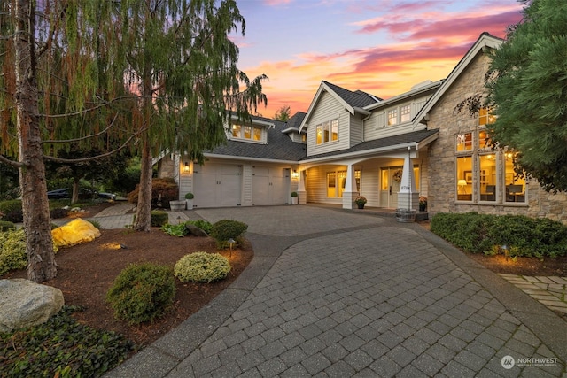 view of front of property featuring stone siding, aphalt driveway, and a porch