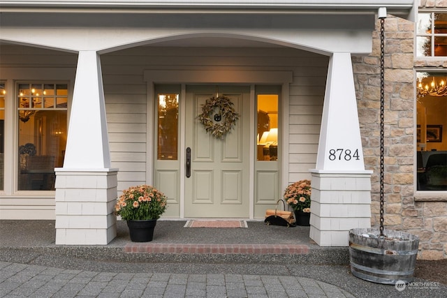 doorway to property with stone siding and a porch