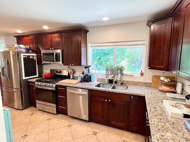 kitchen featuring light tile patterned floors, appliances with stainless steel finishes, light stone counters, and sink