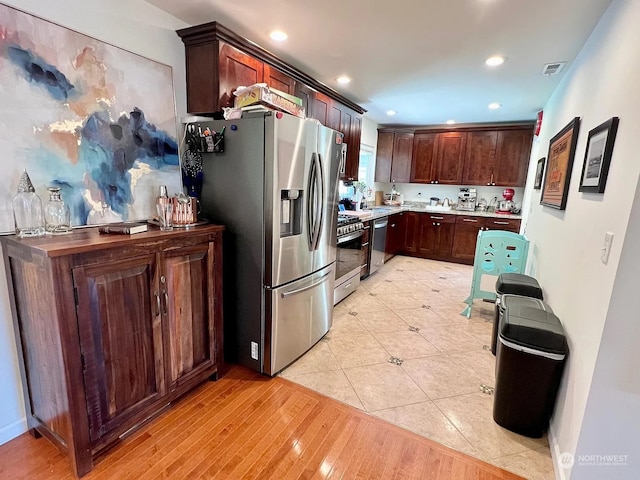 kitchen with light wood-type flooring, stainless steel appliances, and dark brown cabinetry