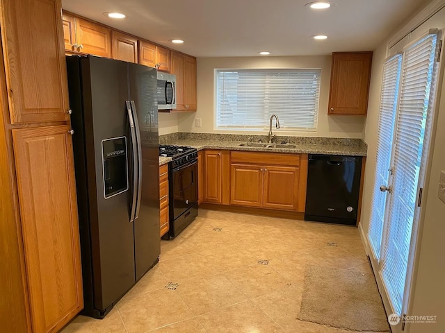 kitchen with black appliances, stone countertops, and sink