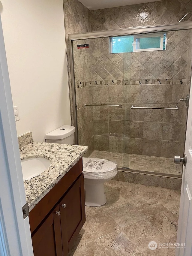 bathroom featuring vanity, toilet, and a shower with shower door