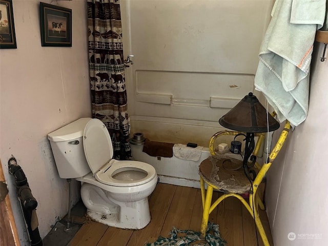 bathroom with a shower with shower curtain, toilet, and wood finished floors