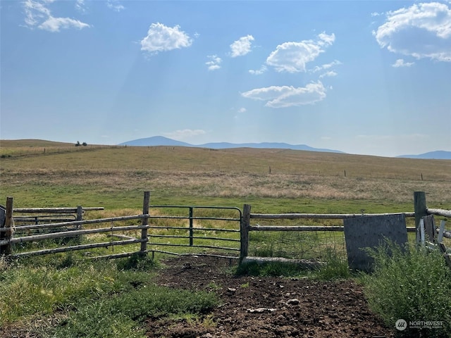 view of yard featuring a rural view, fence, and a mountain view