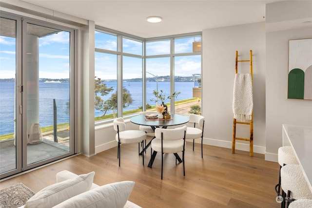 dining space with light wood-type flooring, baseboards, and a water view