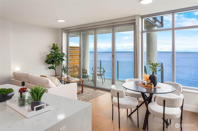 dining area featuring recessed lighting, light wood-style flooring, and a water view