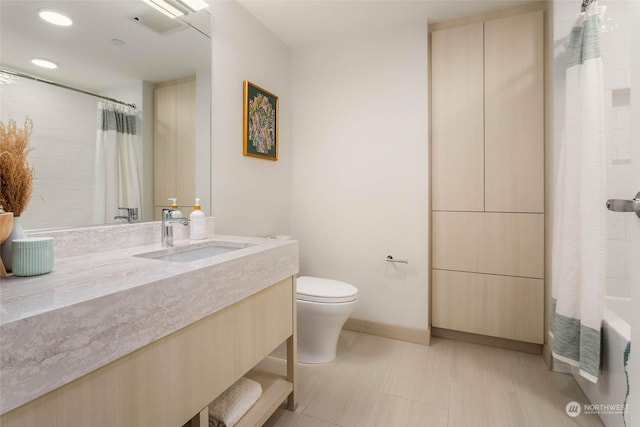 full bathroom with baseboards, toilet, and vanity