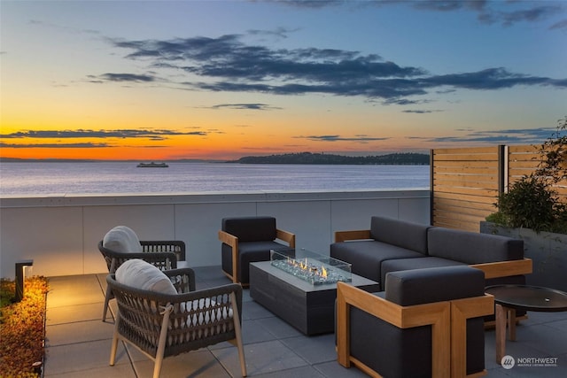 view of patio with an outdoor living space with a fire pit and a water view