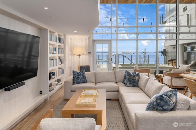 living room featuring built in shelves, a wall of windows, and a water view