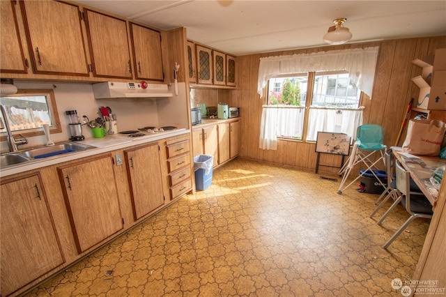 kitchen with white gas stovetop, sink, and wooden walls