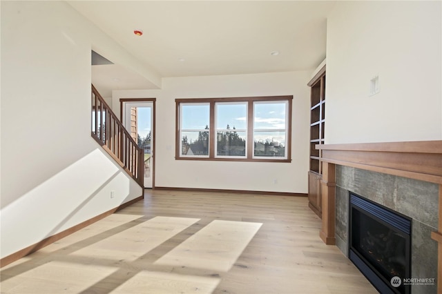 unfurnished living room featuring a healthy amount of sunlight, a fireplace, and light hardwood / wood-style floors