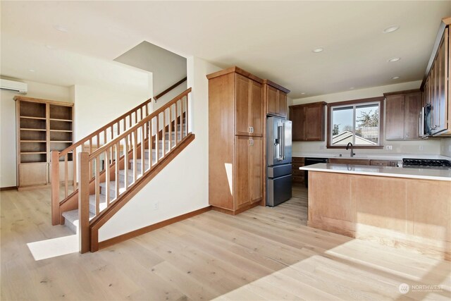 kitchen featuring sink, appliances with stainless steel finishes, a wall mounted air conditioner, kitchen peninsula, and light wood-type flooring